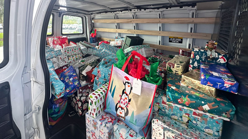 Wrapped holiday gifts loaded into a van for delivery.